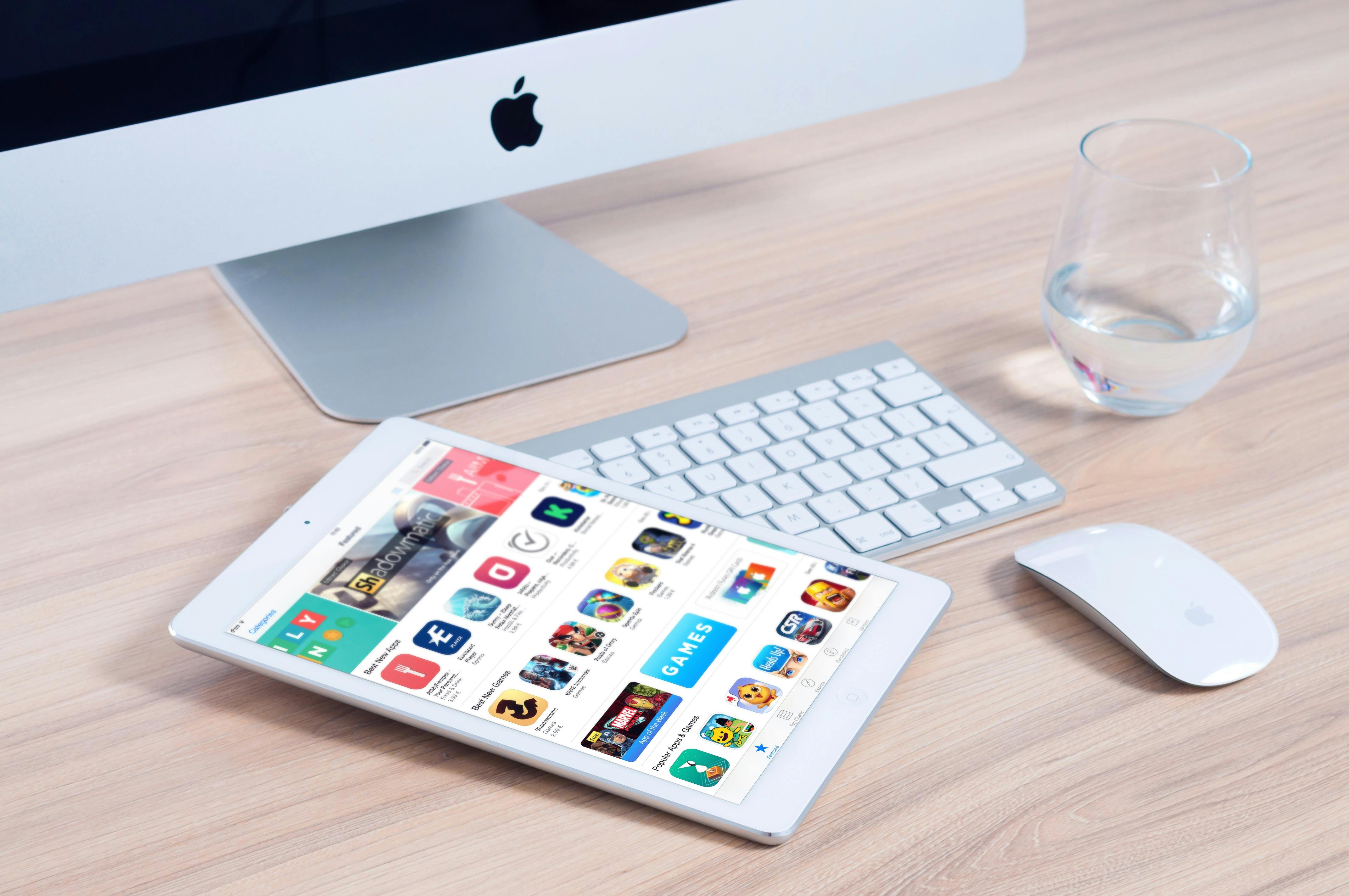 Sleek home office setup featuring an iMac and iPad showcasing apps.